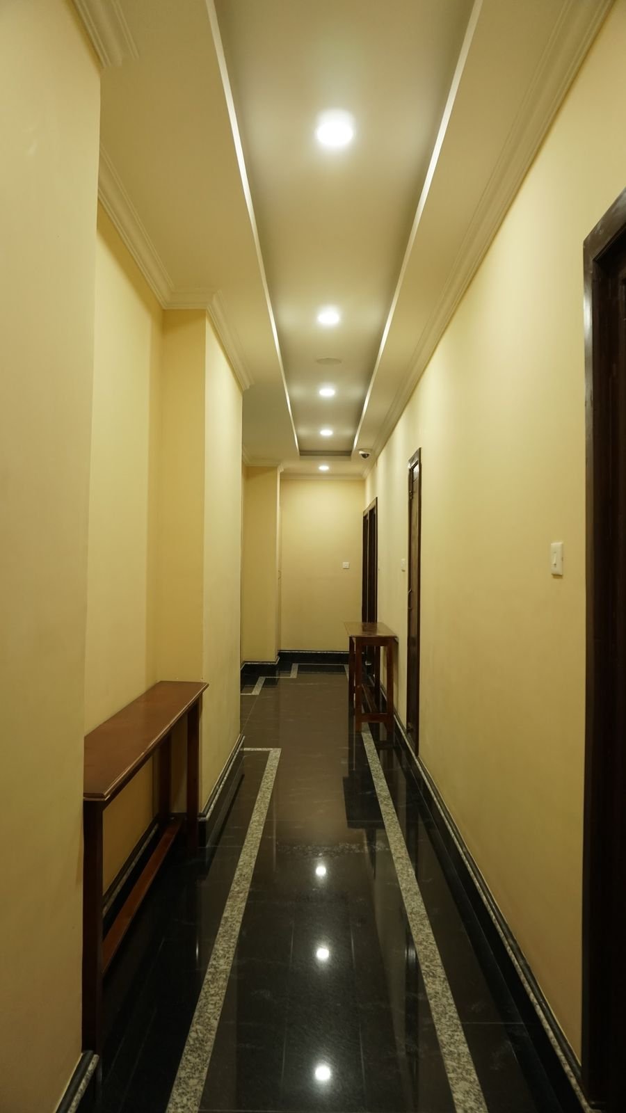 A guest corridor running the length of the floor, polished dark floor and warm downlights
