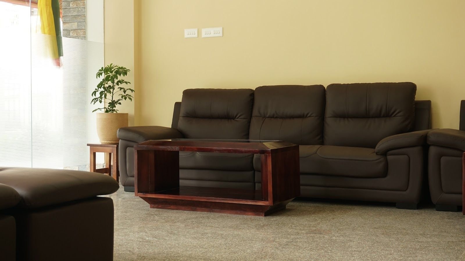 The lounge: dark leather sofas set around a low wooden table, with a plant in the corner