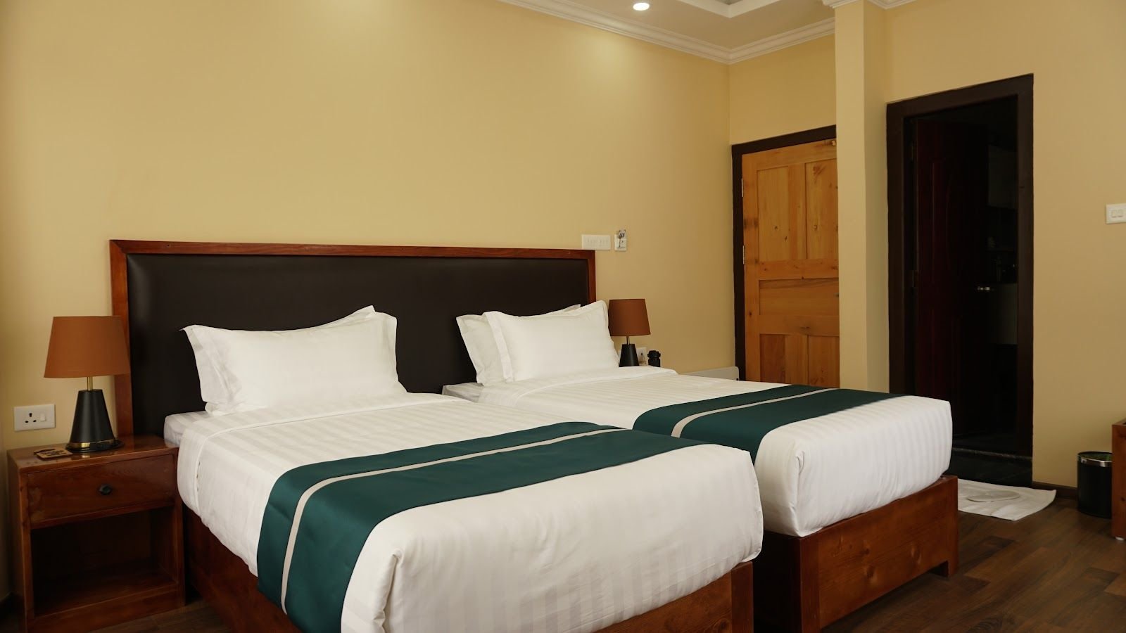 A twin room seen from the doorway, two beds against a padded headboard