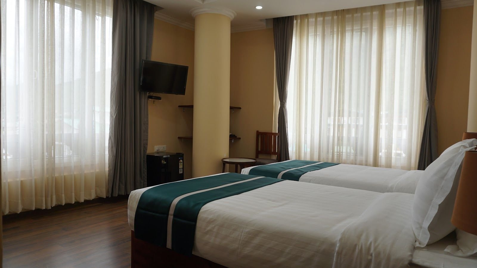 Twin beds beside tall windows hung with sheer curtains