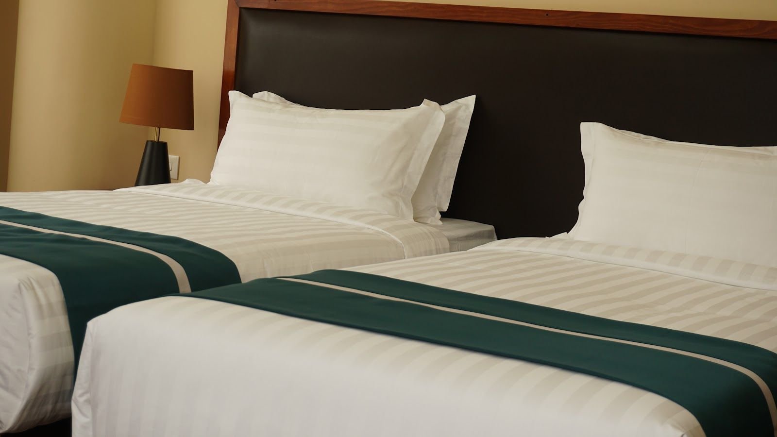 Two single beds side by side, each with white linen and a teal runner