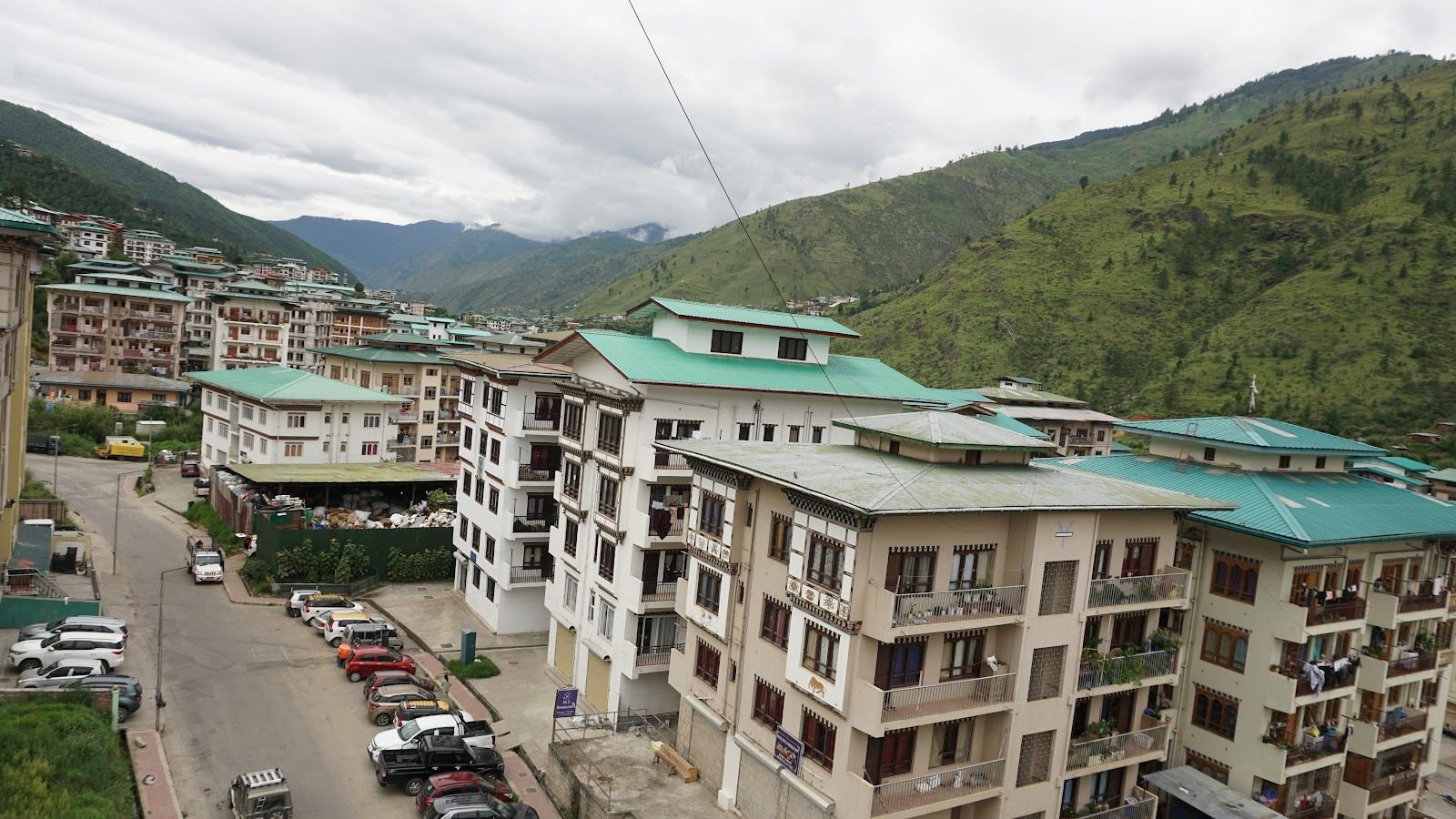 Thimphu below the hotel — rooftops and a street running between buildings, with forested hills rising behind